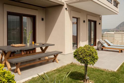 a patio with a wooden table and a bench at Thyme Sea View Apartments by 8essentially in Souda