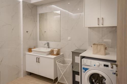 a white bathroom with a washing machine and a sink at Thyme Sea View Apartments by 8essentially in Souda