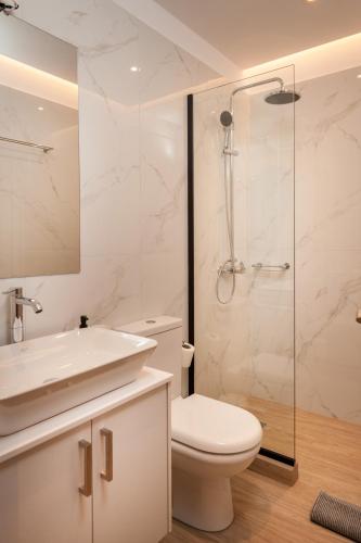 a white bathroom with a toilet and a shower at Thyme Sea View Apartments by 8essentially in Souda
