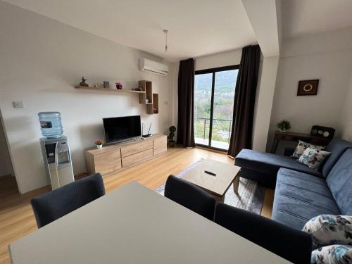 a living room with a blue couch and a tv at Kyrenia Comfort Apartments in Kérynia