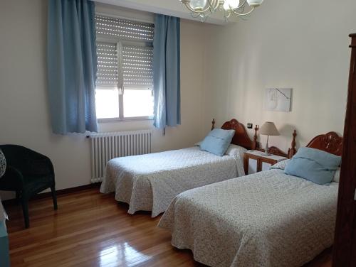 a bedroom with two beds and a window with blue curtains at Casa Pepa in Cambados