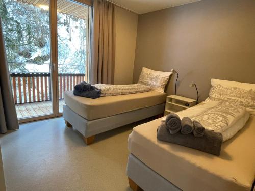 2 Betten in einem Zimmer mit Fenster in der Unterkunft Selva Mountain Apartment in Flims