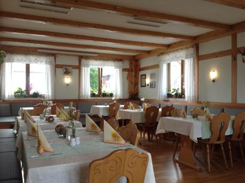 un comedor con mesas, sillas y ventanas en Gasthof Oberer Wirt en Kipfenberg