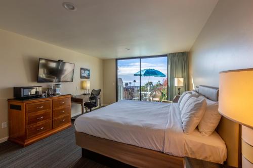 a hotel room with a bed and a window with a view at Moonlight Beach Motel in Encinitas
