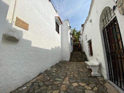 an alley with a white building with a door and a bench at Hotel Aldea Plaza in Doradal