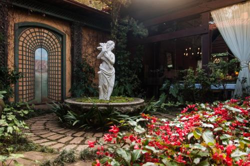 a statue of a woman in a garden with flowers at Pousada Parador Santarém in Itaipava