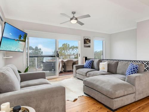 a living room with two couches and a flat screen tv at Villa Killara by Experience Jervis Bay in Vincentia