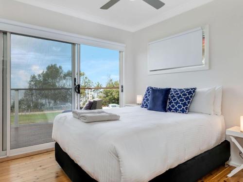 a bedroom with a large bed and a large window at Villa Killara by Experience Jervis Bay in Vincentia