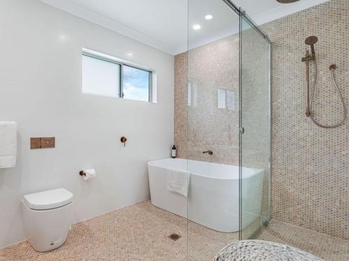 a bathroom with a shower and a tub and a toilet at Villa Killara by Experience Jervis Bay in Vincentia