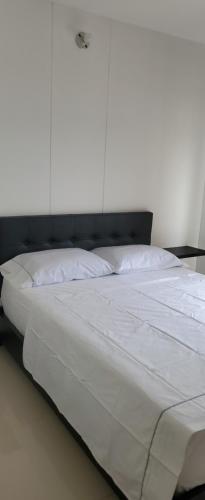 a large white bed with a black headboard in a room at SUPER APARTAMENTO AMOBLADO in Neiva