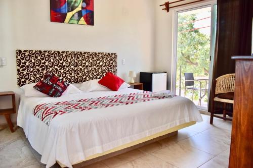 1 dormitorio con 1 cama blanca grande con almohadas rojas en Carri Surf Studio, en Puerto Escondido