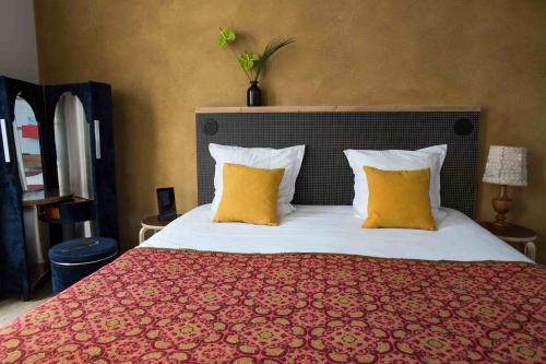 a bedroom with a large bed with two yellow pillows at Hôtel La Nouvelle République & Hammam in Paris