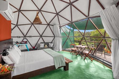 um quarto com uma cama e uma grande parede de vidro em Glamping Serra da Canastra - Casinha de Hortelã - Domo Embaúba em Delfinópolis
