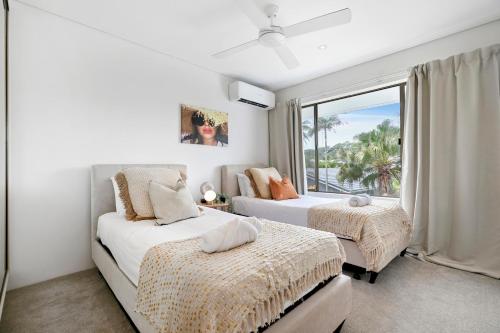 a bedroom with two beds and a large window at The Noosa Apartments in Noosa Heads