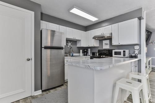 a kitchen with white cabinets and a stainless steel refrigerator at Coastal Waters in New Smyrna Beach