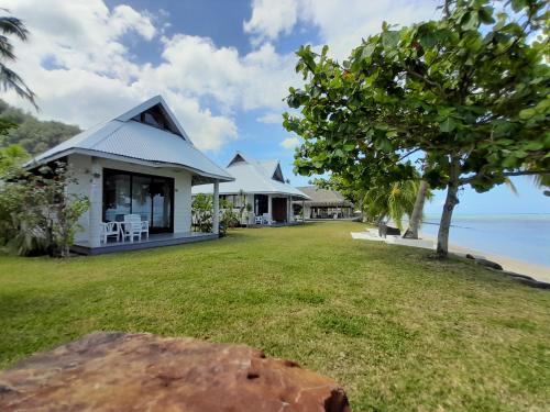 a house with a large yard next to the ocean at Moorea Island Beach Hotel in Moorea