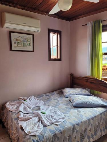 an unmade bed in a bedroom with a window at Casa em Paraty a 7 min. do Centro histórico in Paraty