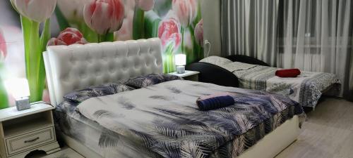 a bedroom with two beds with flowers on the wall at уютные апартаменты на Брестской 171 in Pinsk