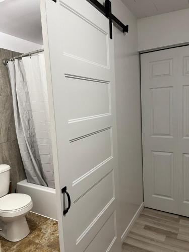 a white door in a bathroom with a toilet at Les studios de la mer in Matane