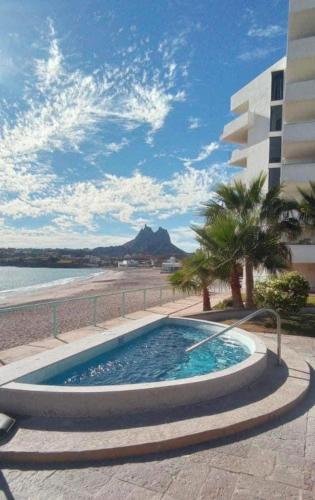 a swimming pool next to a beach and a building at Condominio Posada 314 San Carlos in San Carlos