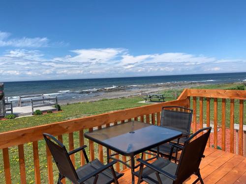 a table and chairs on a deck with the beach at Les studios de la mer in Matane