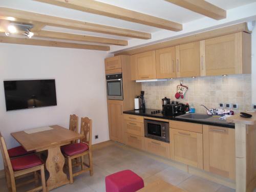 une cuisine avec des placards en bois et une petite table avec une table dans l'établissement Alpine Lodge 3, aux Contamines-Montjoie