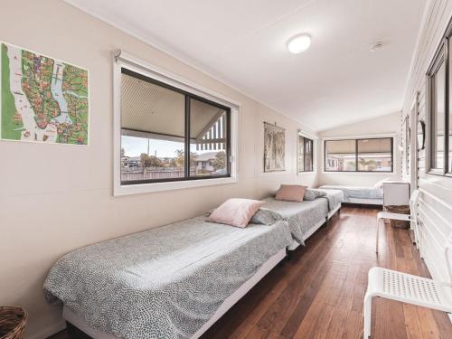 a row of beds in a room with windows at Rosena - The Classic Beach House - 5 Cashmore Street in Evans Head