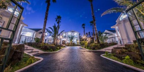 a driveway leading to a mansion with palm trees at Jeju Washington Pension in Seogwipo