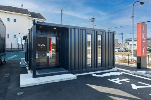 a black container building in a parking lot at HOTEL R9 The Yard Inabe in Kuwana