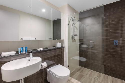 a bathroom with a sink and a toilet and a shower at Meriton Suites Mascot Central in Sydney