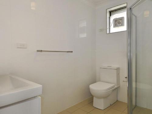 a white bathroom with a toilet and a sink at Beachside Getaway in Kiama