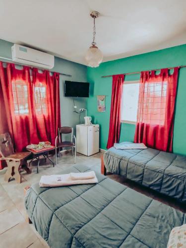 a bedroom with two beds and red curtains at Hospedaje Familiar Raza Mistica in Villa Unión