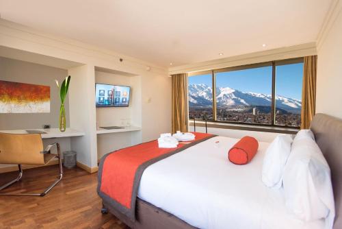 a bedroom with a bed and a desk and a window at Boulevard Suites Ferrat in Santiago