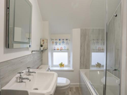 a bathroom with a sink and a toilet and a tub at The Pink House in Rhosneigr