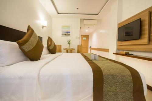 a bedroom with a large white bed and a flat screen tv at Commander Suites de Boracay in Boracay