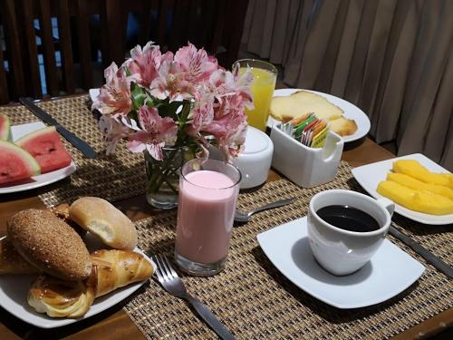 a table topped with plates of food and a pink drink at Hotel Tara Machupicchu in Machu Picchu