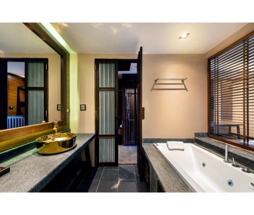 a bathroom with a large tub and a sink at Nirvana Beach Resort, Koh Lanta SHA Extra Plus in Ko Lanta