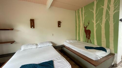 two beds in a room with a painting on the wall at Nuevo Oeste in Acacías
