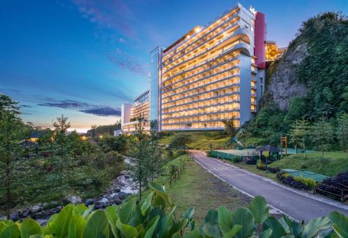 a building with a road in front of a mountain at Le Eminence Puncak Hotel Convention & Resort in Puncak