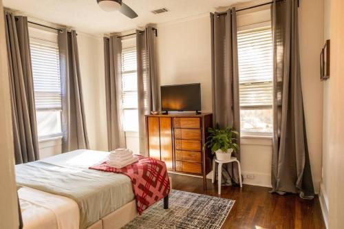 a bedroom with a bed and a tv and windows at J Birds’ Bungalow in the heart of Midtown in Memphis