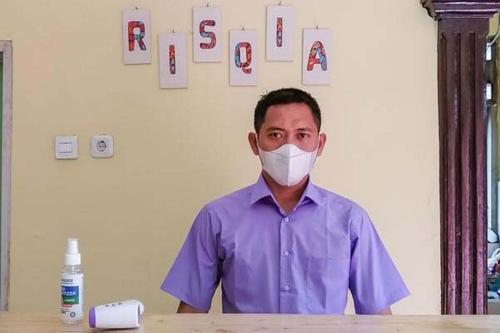 un homme portant un masque assis à une table dans l'établissement Risqia Syariah TOD M1 Bandara Soekarno Hatta Mitra RedDoorz, à Sewan