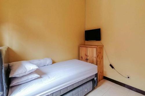 Dormitorio pequeño con cama y TV en Risqia Syariah TOD M1 Bandara Soekarno Hatta Mitra RedDoorz en Sewan