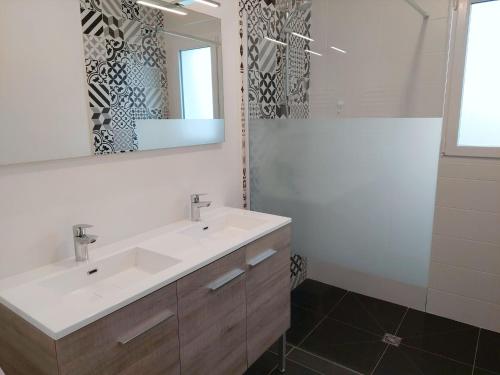 La salle de bains est pourvue d'un lavabo blanc et d'un miroir. dans l'établissement Single-storey holiday home in Cleder, à Cléder