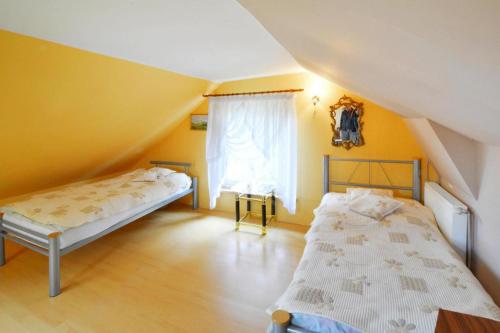 Cette chambre comprend 2 lits dans une chambre dotée de murs jaunes et d'une fenêtre. dans l'établissement holiday home, Spore, à Szczecinek