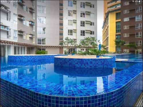 a swimming pool with blue tiles in front of buildings at Studio Fully Furnished in Manila