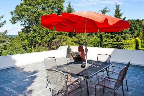 a woman sitting at a table with a red umbrella at Reihenhaus Seeblick, Sommersdorf in Sommersdorf