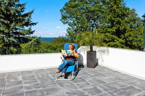 a woman sitting in a chair reading a book at Reihenhaus Seeblick, Sommersdorf in Sommersdorf