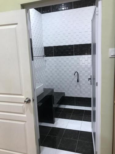 y baño con ducha y azulejos blancos y negros. en Homestay Islam Bandar Tasik Puteri Rawang en Rawang