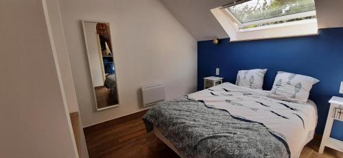 Cet appartement comprend une chambre dotée d'un lit avec un mur bleu et une fenêtre. dans l'établissement 16Bis 1ch, 2-4pers, jardin Les Gîtes Bigoudens, à Plonéour-Lanvern