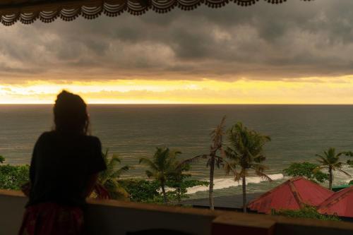 a woman looking out of a window at the ocean at The Lost Hostel, Varkala - Helipad in Varkala